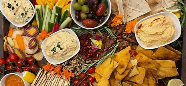 Grazing board with hummus, olives, chips, and crudité